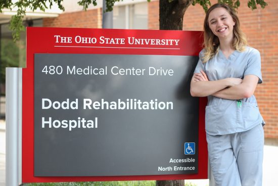 Bethany Frick standing in front of Ohio State University, Dodd Rehabilitation Hospital signage